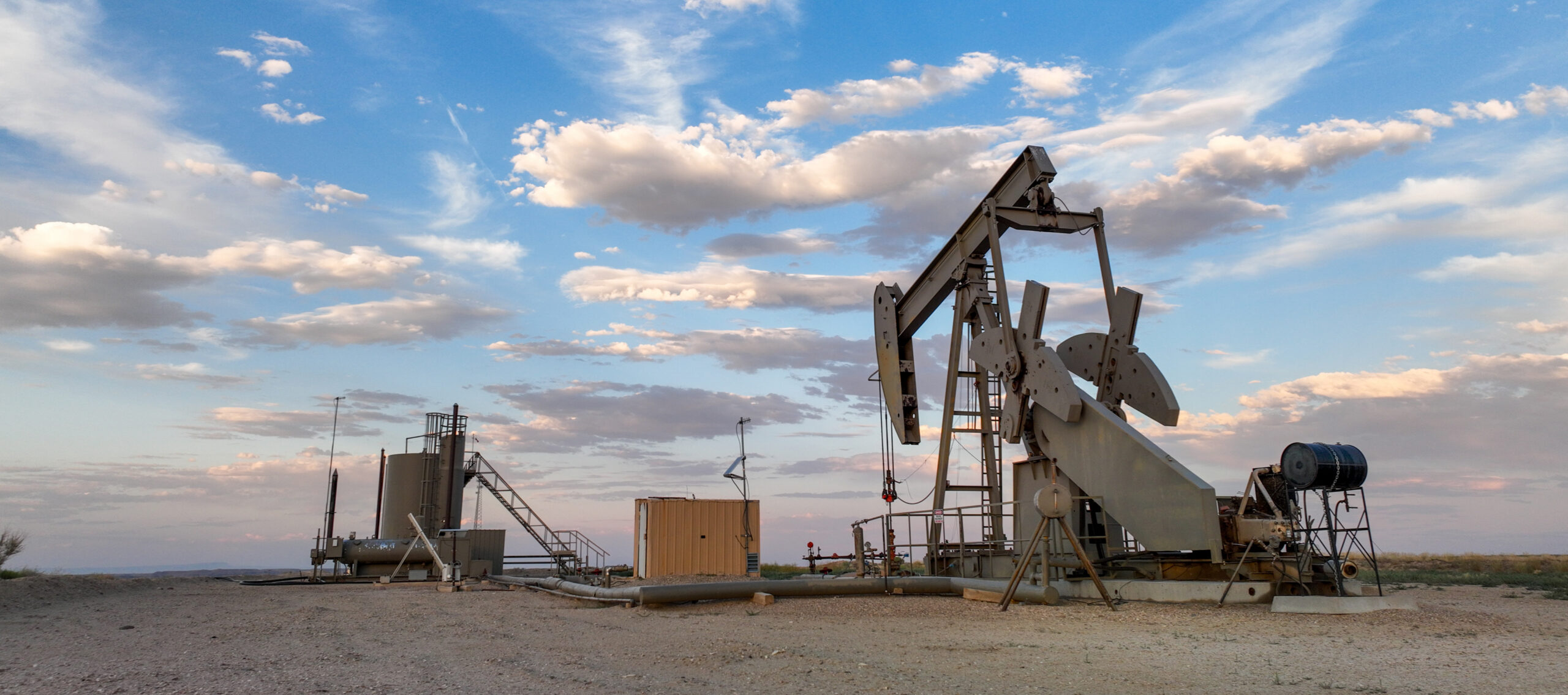 An oil pumpjack operating in the Uinta Basin, Utah under a partly cloudy sky.